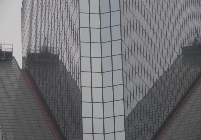 A modern glass skyscraper reflects the iconic Christ the Redeemer statue on an overcast day in Rio de Janeiro