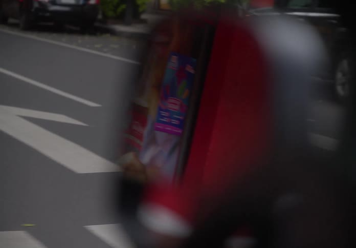 A blurry reflection of a city street passes by in a car's side-view mirror