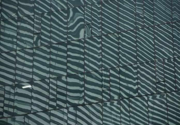 A mesmerizing abstract reflection of wavy lines and distorted shapes on the glass facade of a modern skyscraper