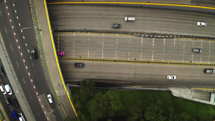 Top-down aerial view of a multi-level highway interchange with heavy rush hour traffic on one side and freely flowing cars on the other