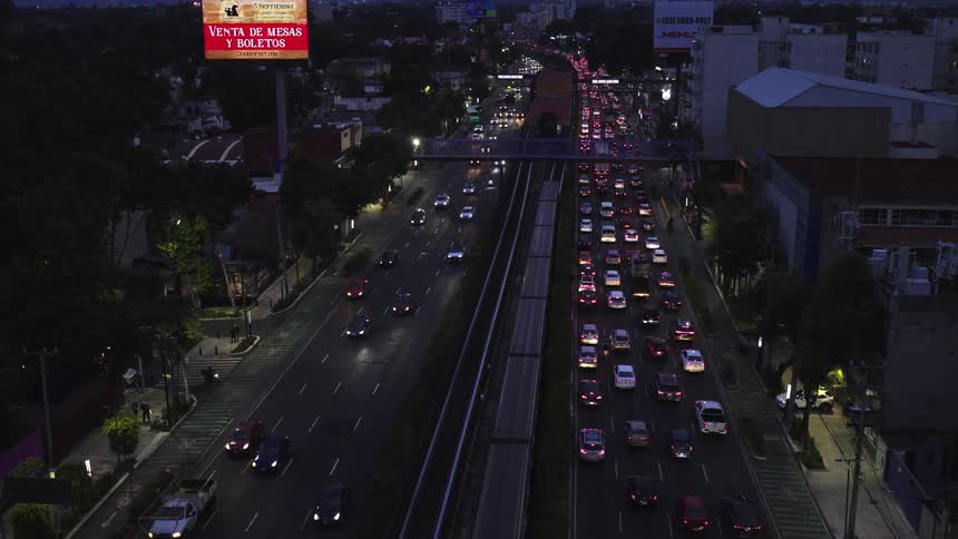 Aerial view of a busy city highway and train tracks with heavy traffic at dusk as the camera slowly pushes forward