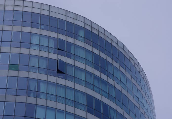 The curved glass facade of a modern hotel or office building under an overcast sky
