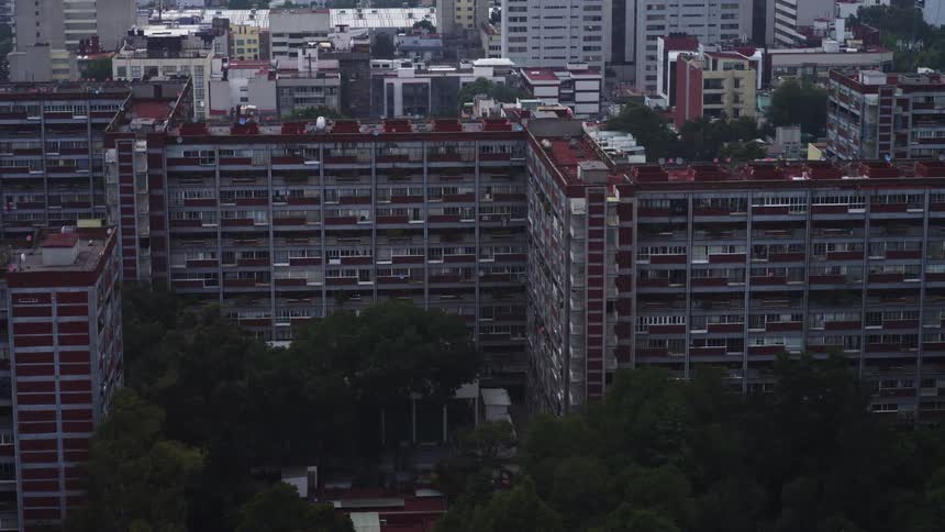 A slow-moving aerial shot captures the facade of a large, vintage apartment building complex in a bustling city