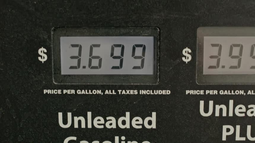 A close-up camera tilt up reveals the price per gallon for unleaded gasoline on a digital gas pump display