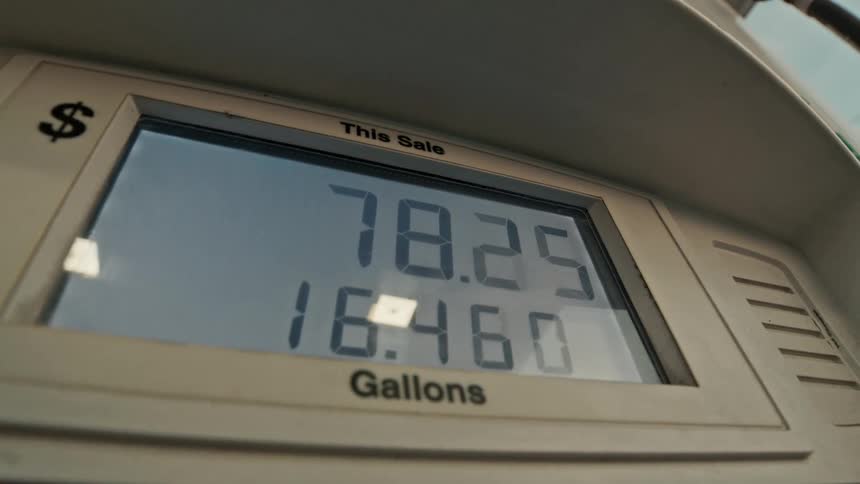 A low-angle close-up shot of a digital gas pump display as the price and gallons rapidly increase while refueling a vehicle