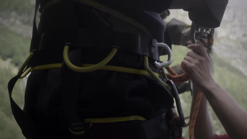 Close-up of rock climbers meticulously checking and adjusting their safety ropes and harness equipment