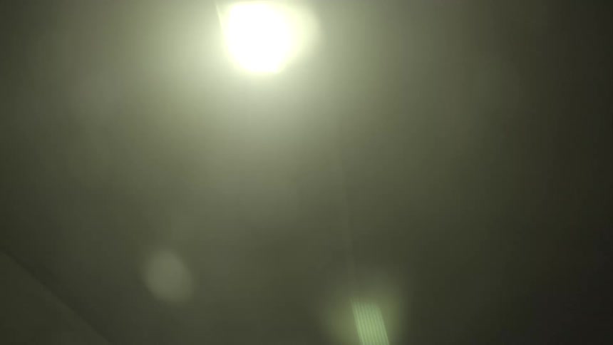 An abstract point-of-view of driving through a dark tunnel at night, with blurry, yellow ceiling lights passing overhead in a hypnotic sequence