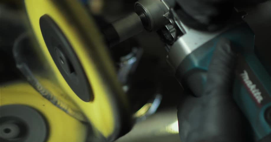 A grinder smooths a piece of metal