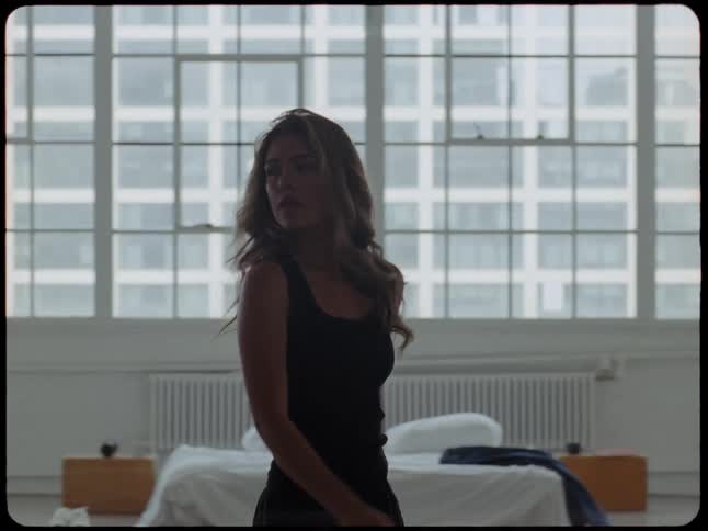 Slow motion profile shot of a beautiful young woman walking thoughtfully through her minimalist city apartment