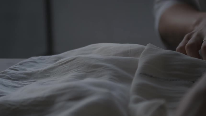 A woman straightens out the layers of a garment on a table