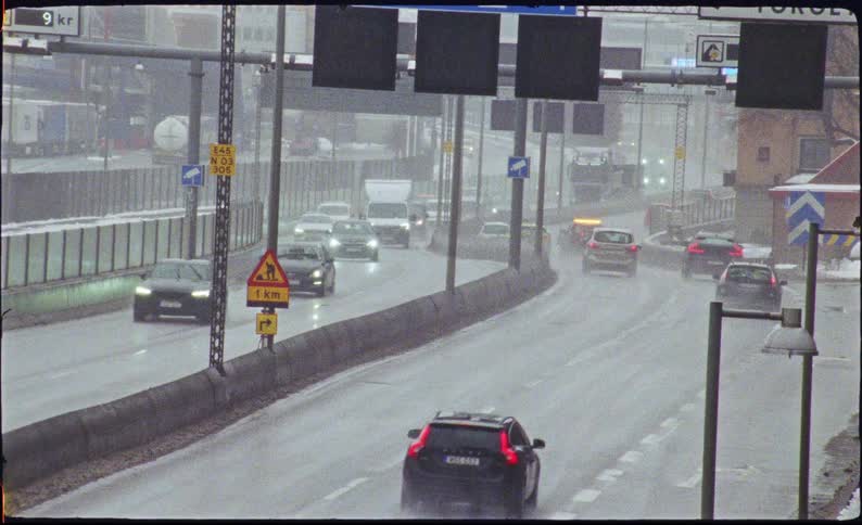 Overcast view of commuter traffic and a tanker truck driving on a wet highway during a rainy day