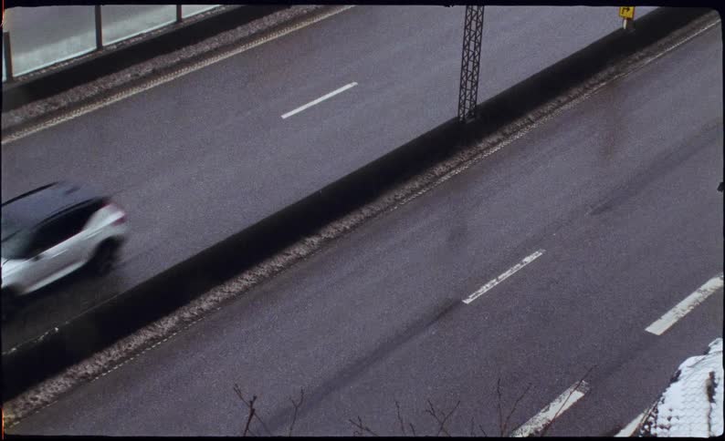 High-angle film footage shows traffic on a wet highway on a gloomy winter day