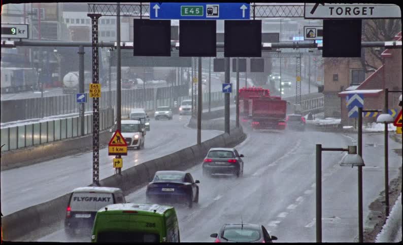 Cars and trucks drive away on a wet, slushy highway during a gloomy winter day