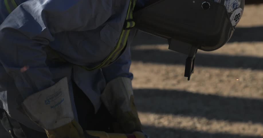A worker is welding metal outside