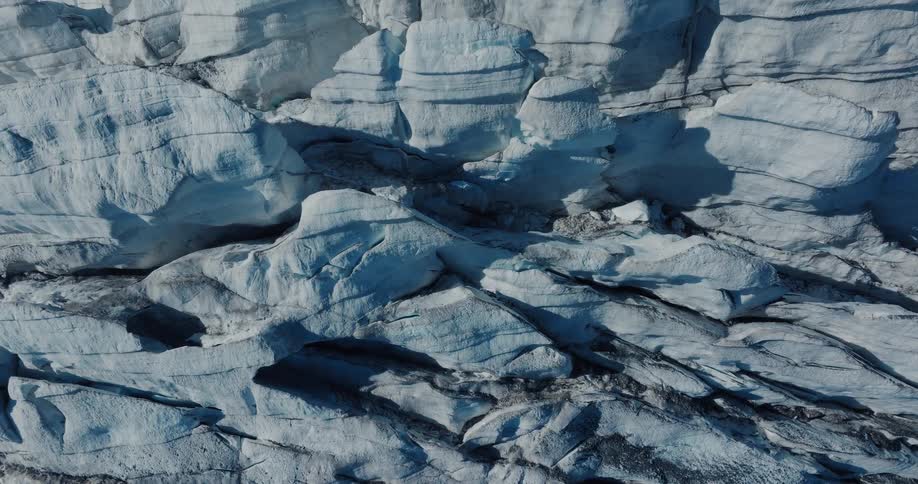 A slow aerial zoom-out reveals the vast and textured surface of a massive glacier