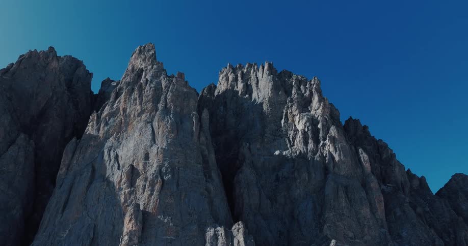 Jagged, grey mountain peaks stand tall against a clear, brilliant blue sky