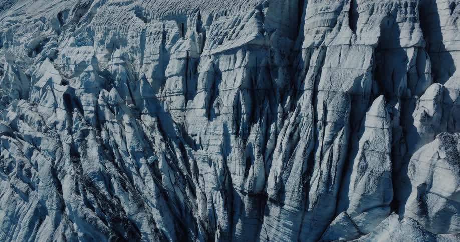 A detailed time-lapse reveals the changing shadows across the rugged and cracked surface of a massive glacier