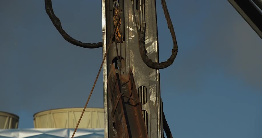 A crane lifts a rusty metal beam