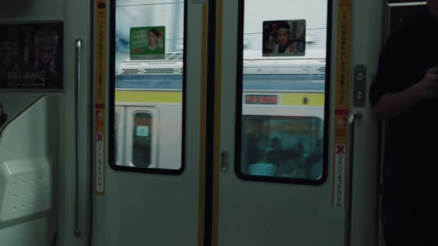 Looking through the doors of a moving subway car as another train travels alongside on a parallel track