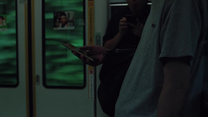 A person scrolls through their smartphone on a moving train, with the blurred green scenery passing quickly by the window