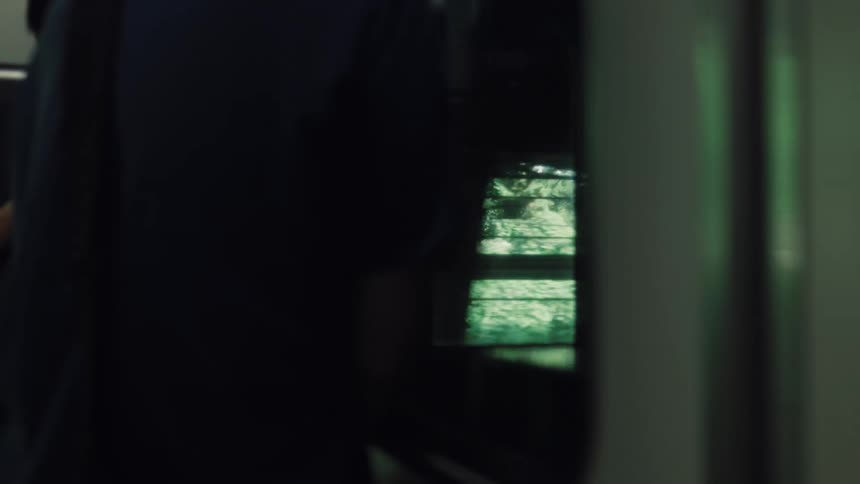 Close up of a speeding train window shows the passing green landscape and city