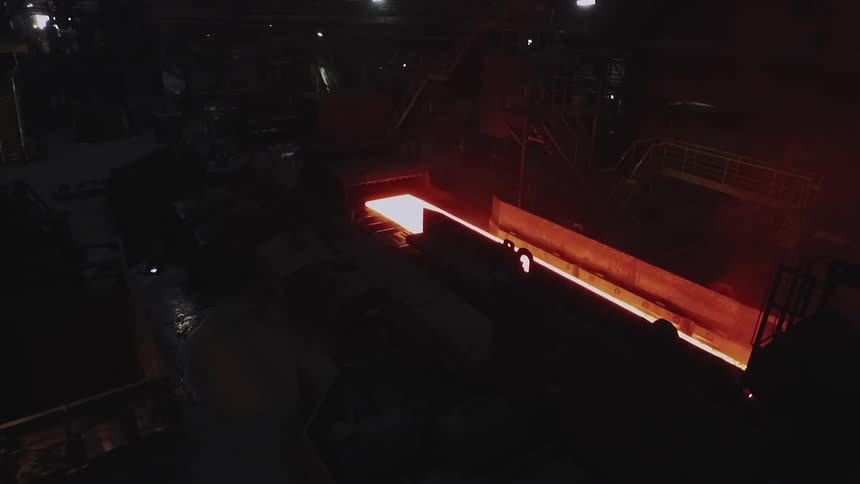 Molten looking sheet rolling on a conveyor belt in a factory