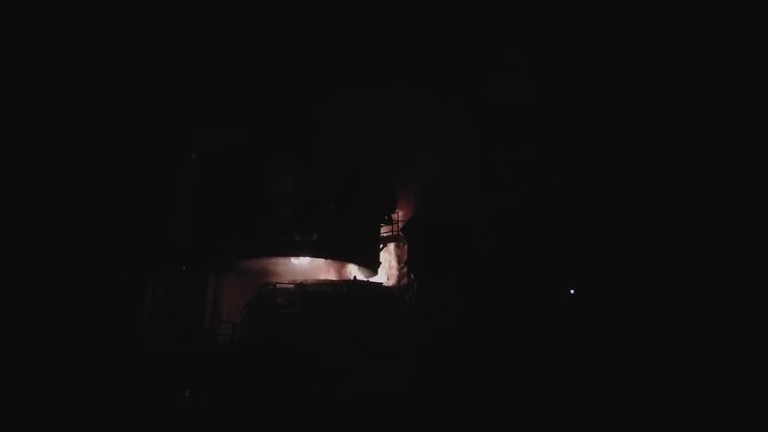 Ahead you can see flames and smoke rising in the dark