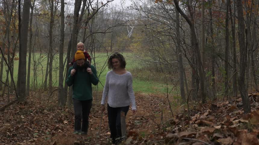 Man woman and child walk through woods on a fall day
