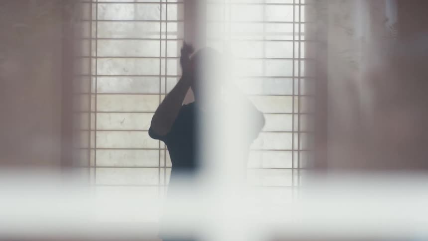 A focused Asian man practices a slow and deliberate martial art routine in a serene dojo with shoji screens