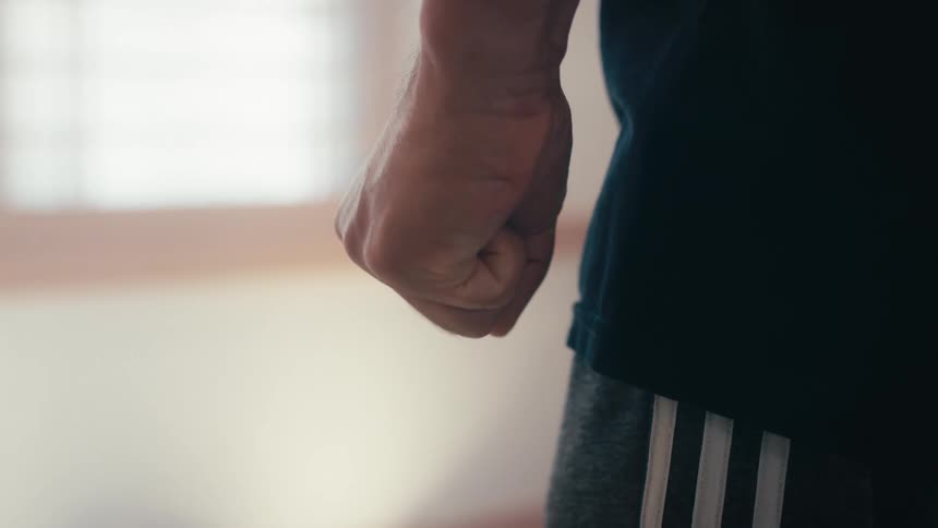 A close-up shot of an angry man's hand clenching into a tight fist in slow motion