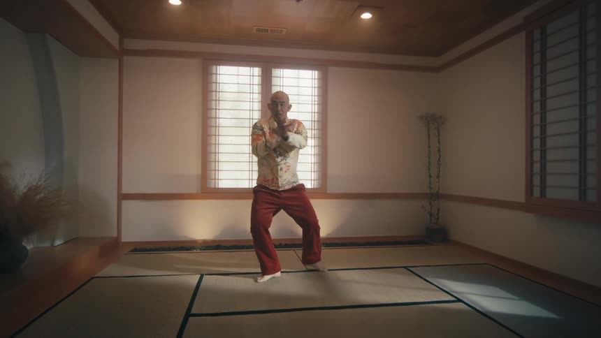 A man practices a slow, flowing martial art in a traditional Japanese-style room with tatami mats