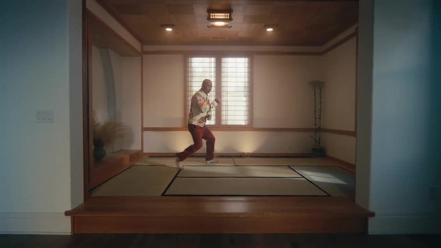 Slow zoom out on a barefoot man practicing the art of Tai Chi in a serene Japanese-style dojo