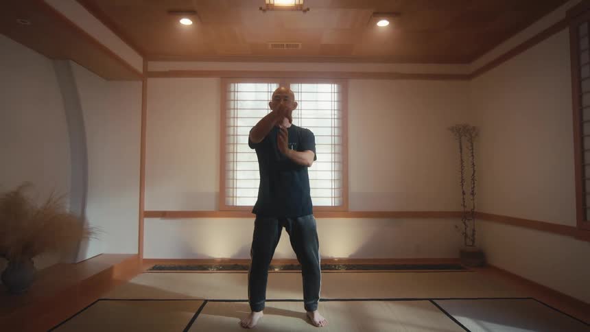 An older bald man practices the meditative art of Tai Chi with slow, flowing movements in a tranquil, Japanese-style dojo