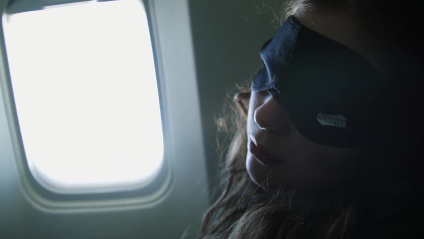 Woman wearing a sleeping mask on an airplane