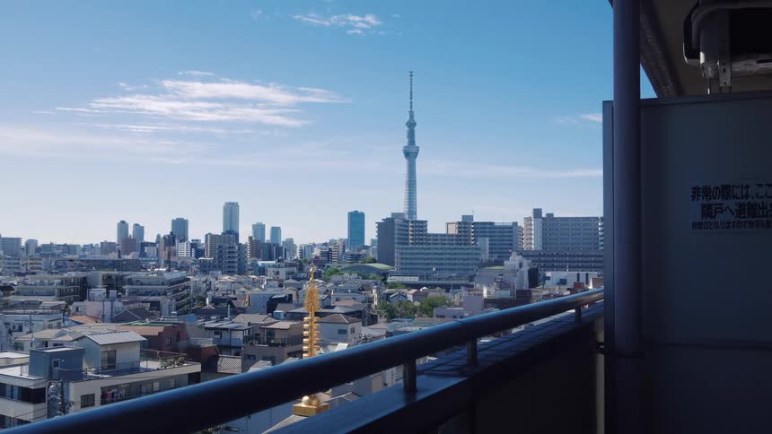 A tranquil wide view of the Tokyo city skyline and the iconic Skytree from a high-rise balcony on a clear, sunny day