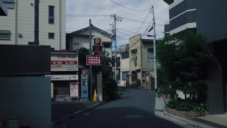 A static view of a quiet, narrow street in a residential neighborhood of Japan on a cloudy day