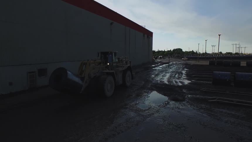 Tractor drives alongside a large building