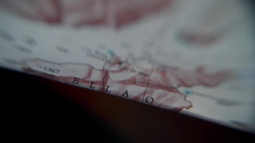 A close-up, slow pan across a vintage topographical map details a remote arctic region, evoking a sense of planning and adventure