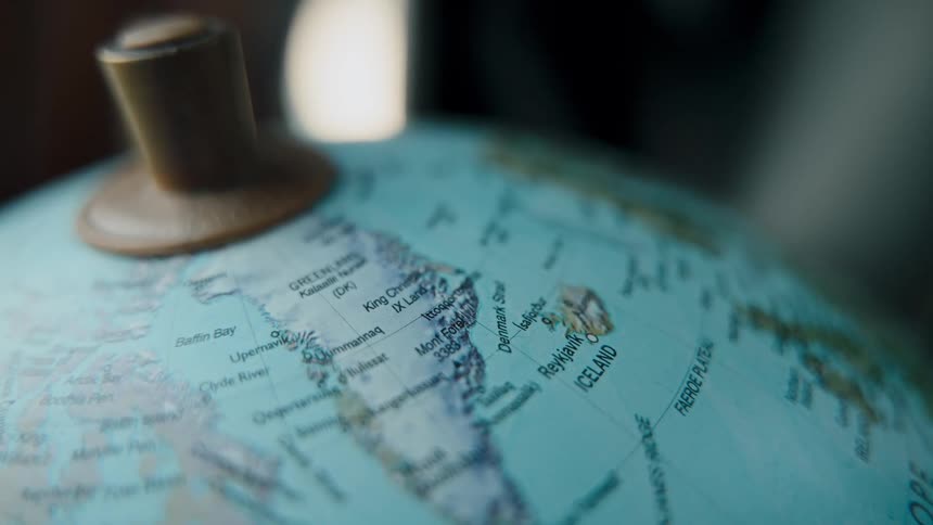 A detailed, moody close-up of a globe slowly rack focusing from Greenland to Iceland