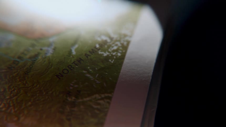 An extreme close-up shot slowly pans across a detailed map of North America