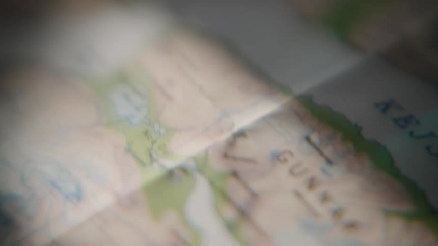 A close-up shot slowly pans and rack focuses across a topographical map, suggesting adventure and exploration