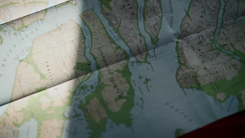 Sunlight and shadows pass over a vintage geographical map of an arctic fjord region