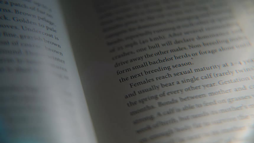 A close-up shot of an open book focuses on text describing animal behavior