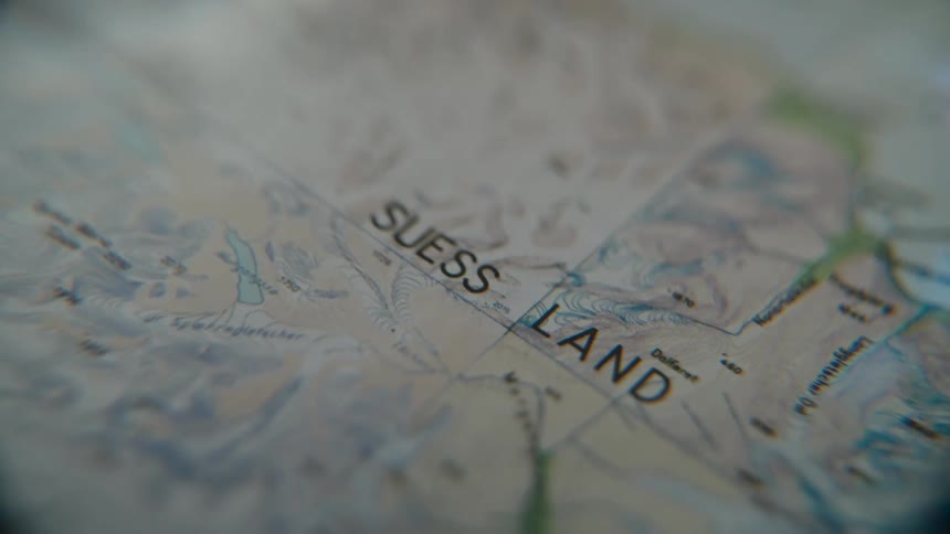 A detailed macro shot focuses on the 'Suess Land' area of a topographical map