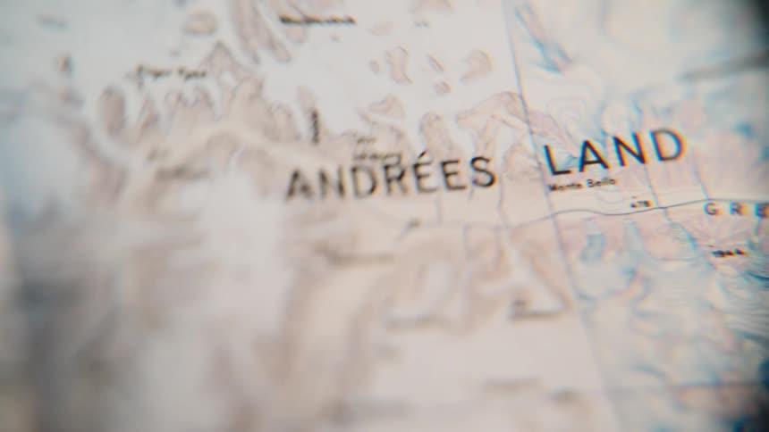 A shaky and blurry close-up shot pans across a vintage topographical map of a remote land