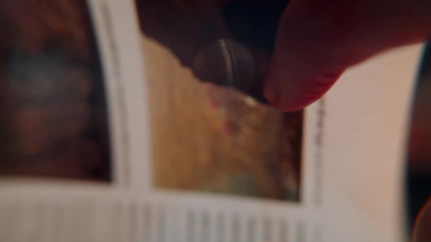A close-up, slow-motion shot of a finger with red nail polish turning the page of a book or magazine