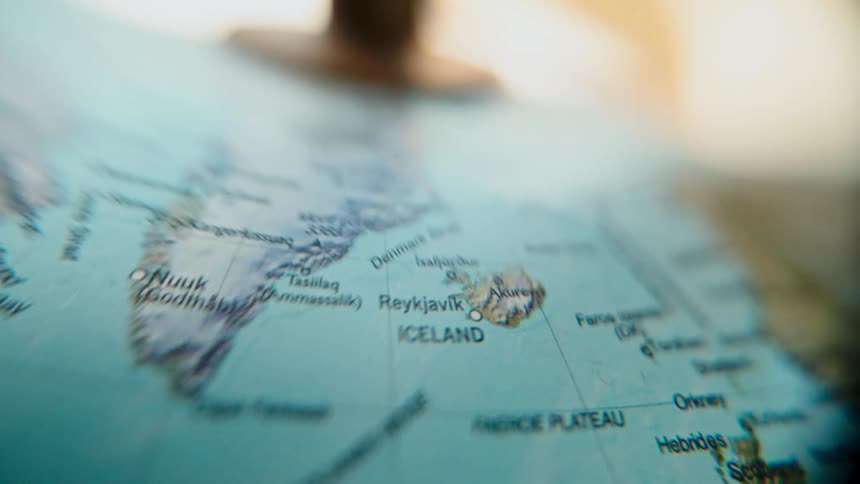 A shallow depth of field close-up shot reveals the countries of Greenland and Iceland on a world globe