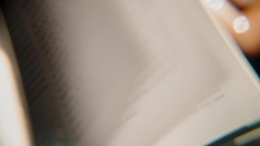 A close-up view of pages being turned in an animal encyclopedia featuring illustrations of lizards, fish, and birds