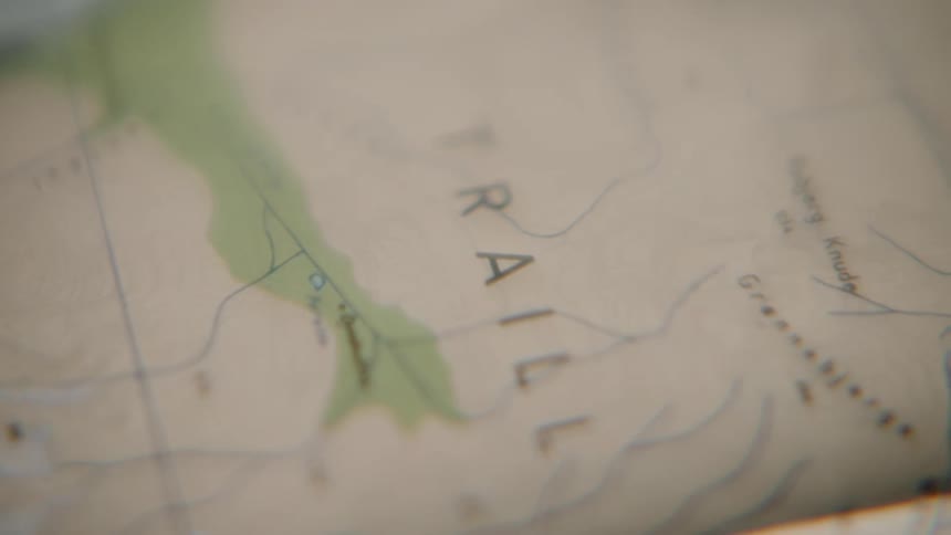 An extreme close-up shot pans across a vintage-style topographical trail map