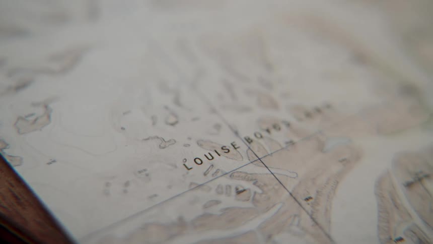 A slow focus pull reveals the name 'Louise Boyds Land' on an old topographical map